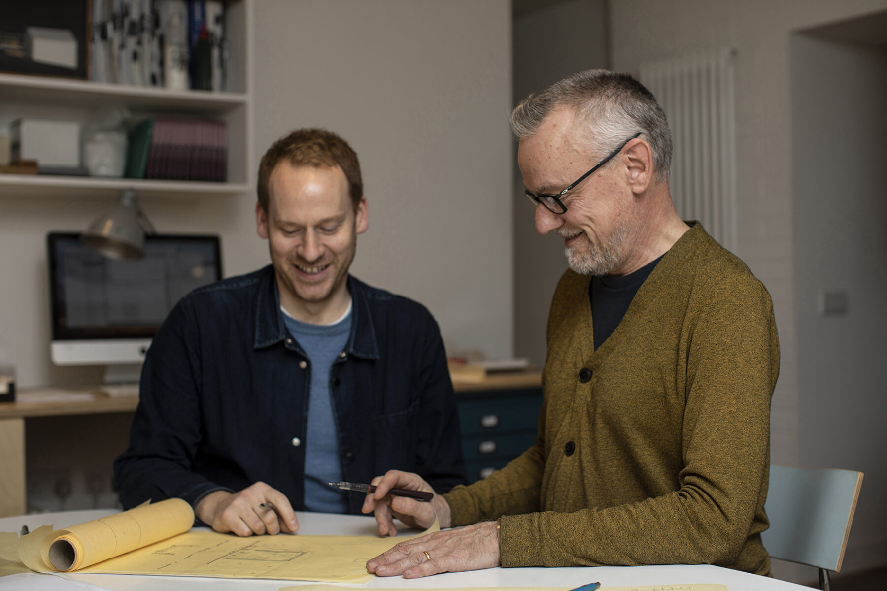 Robin Livingstone and Malcolm Fraser of Fraser Livingstone Architects sitting at a desk in their office.