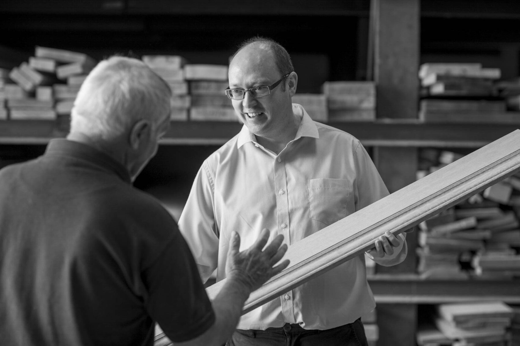 Black and white photo of Harry Taylor director speaking to a joiner about skirting detail.