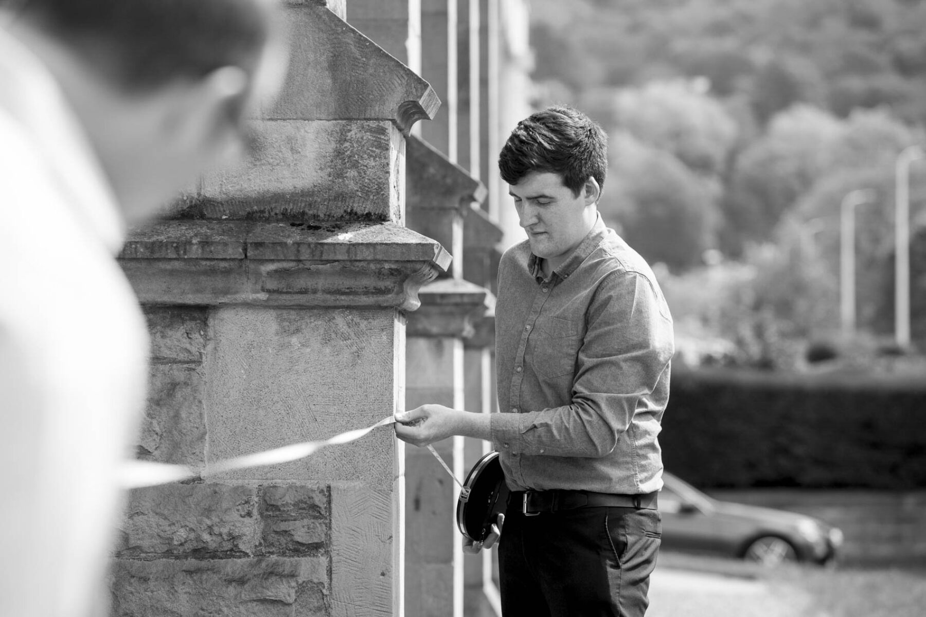 Photo of Harry Taylor staff with measuring tape doing a building survey.