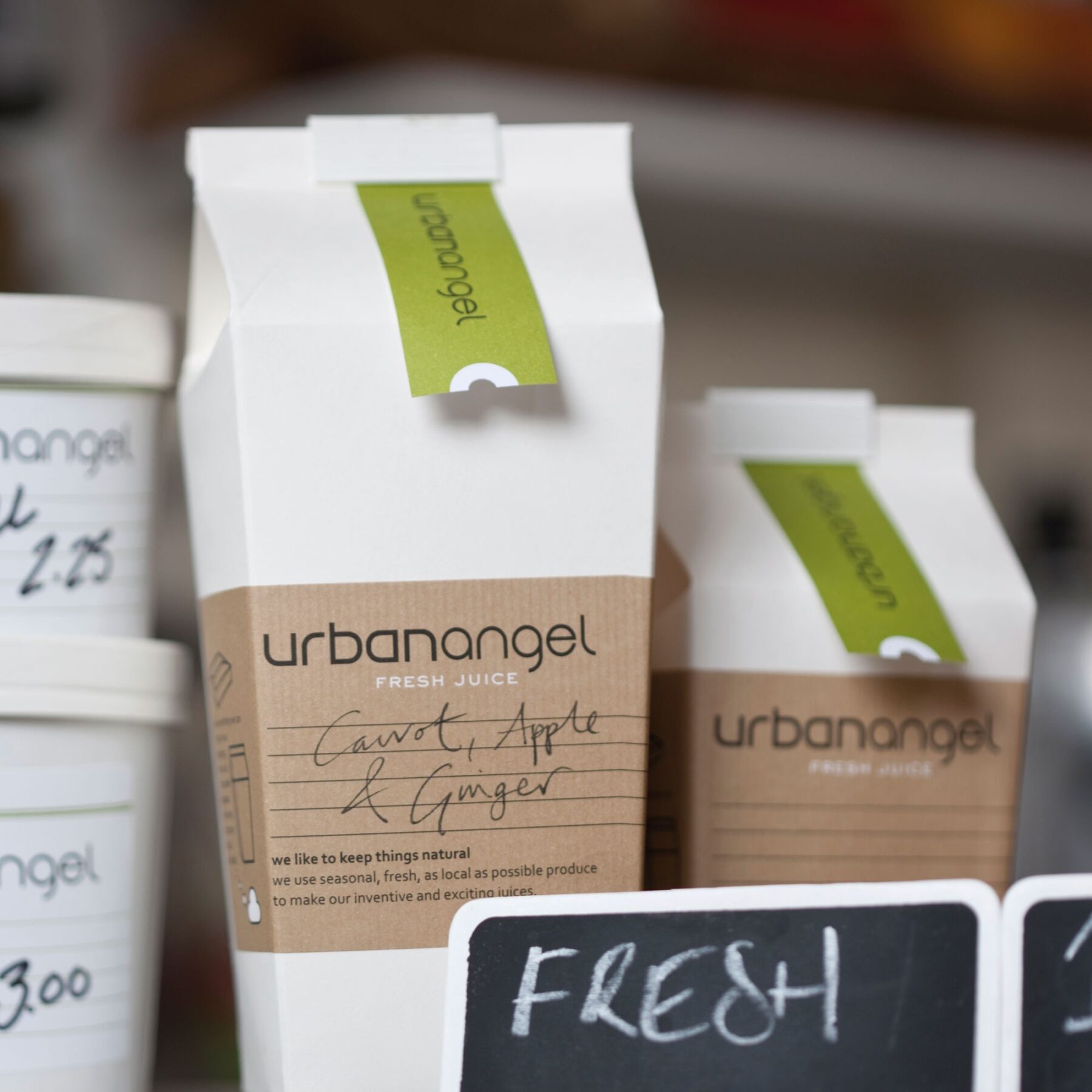 Urbanangel take-away packaging cartons with kraft labels and green branded neck labels.