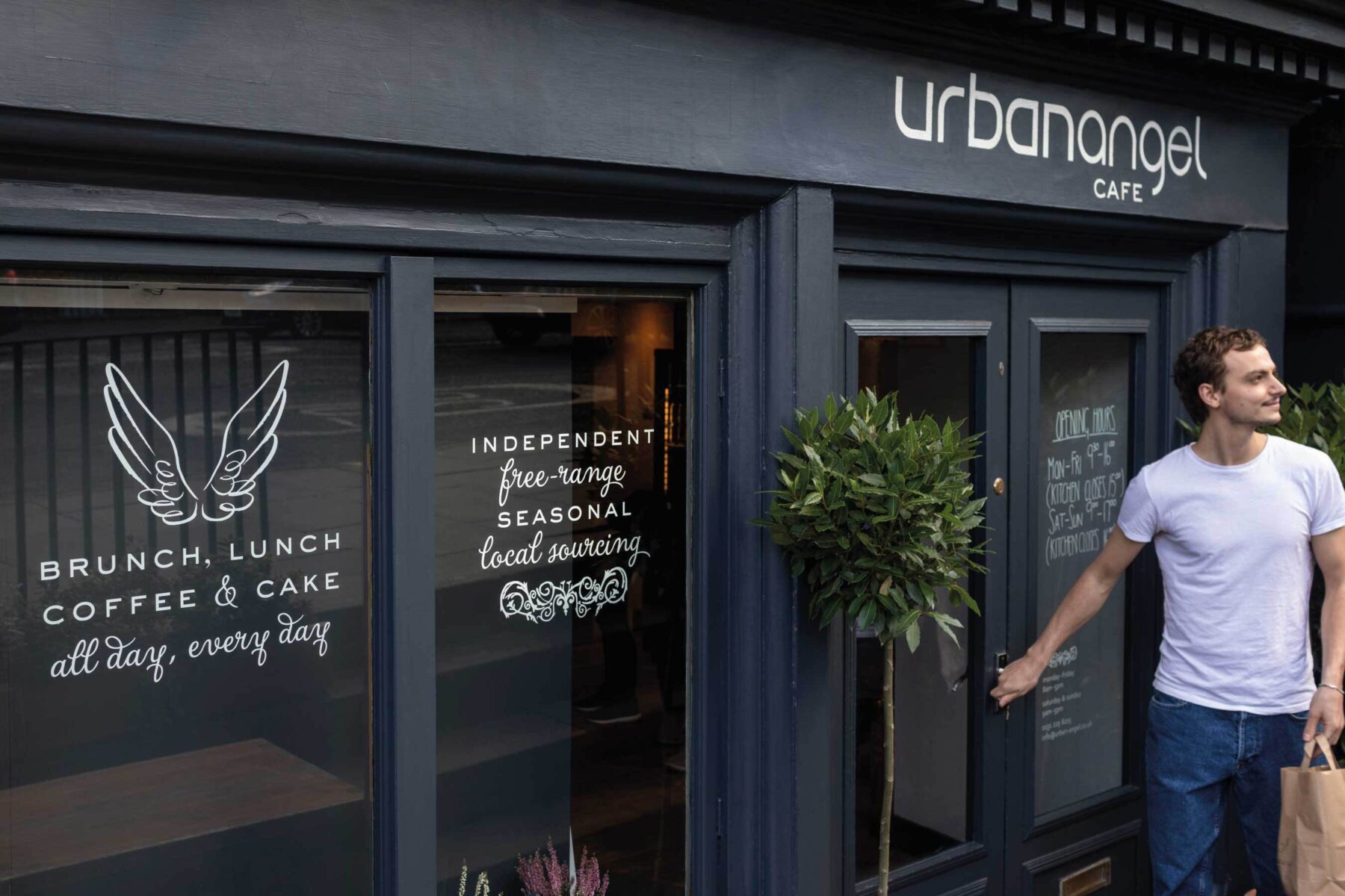 Urbanangel exterior photo. Man leaving the cafe with take away in paper bag.